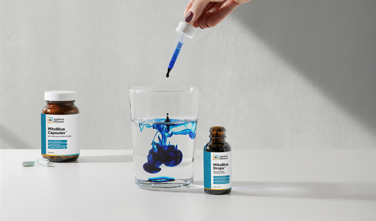 MitoBlue™ capsules and drops bottles beside a glass of water and a dropper